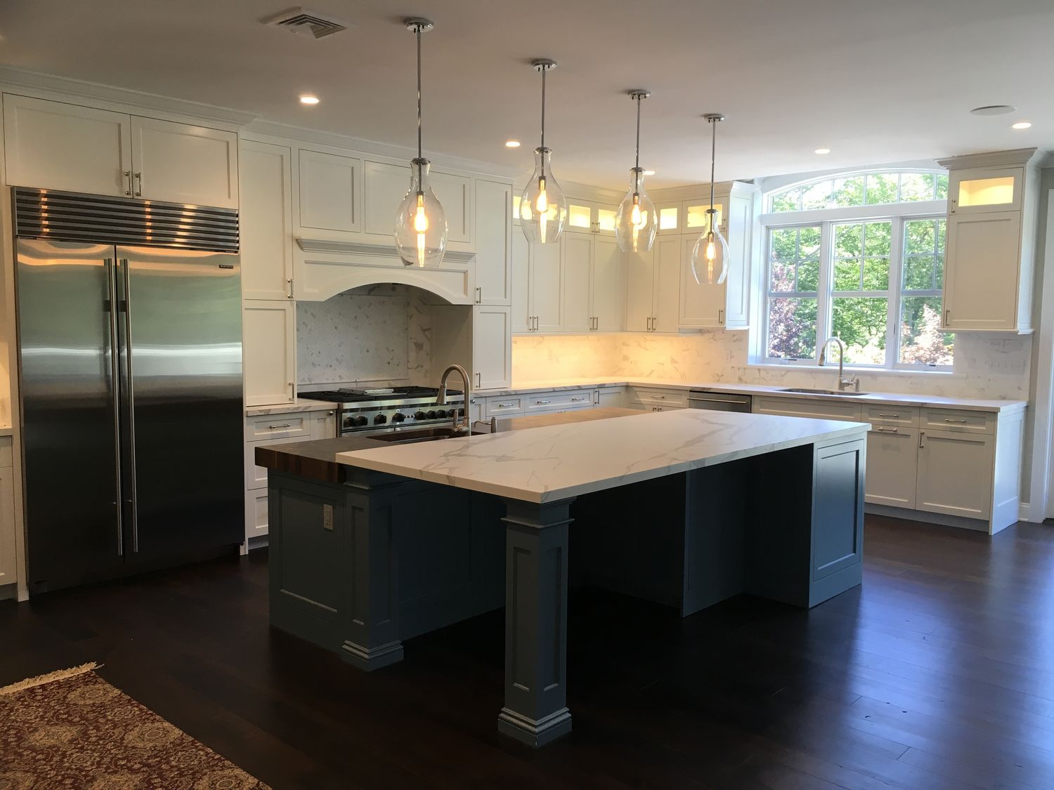 White kitchen remodel with gray island and glass pendants by Division Seven Millwork