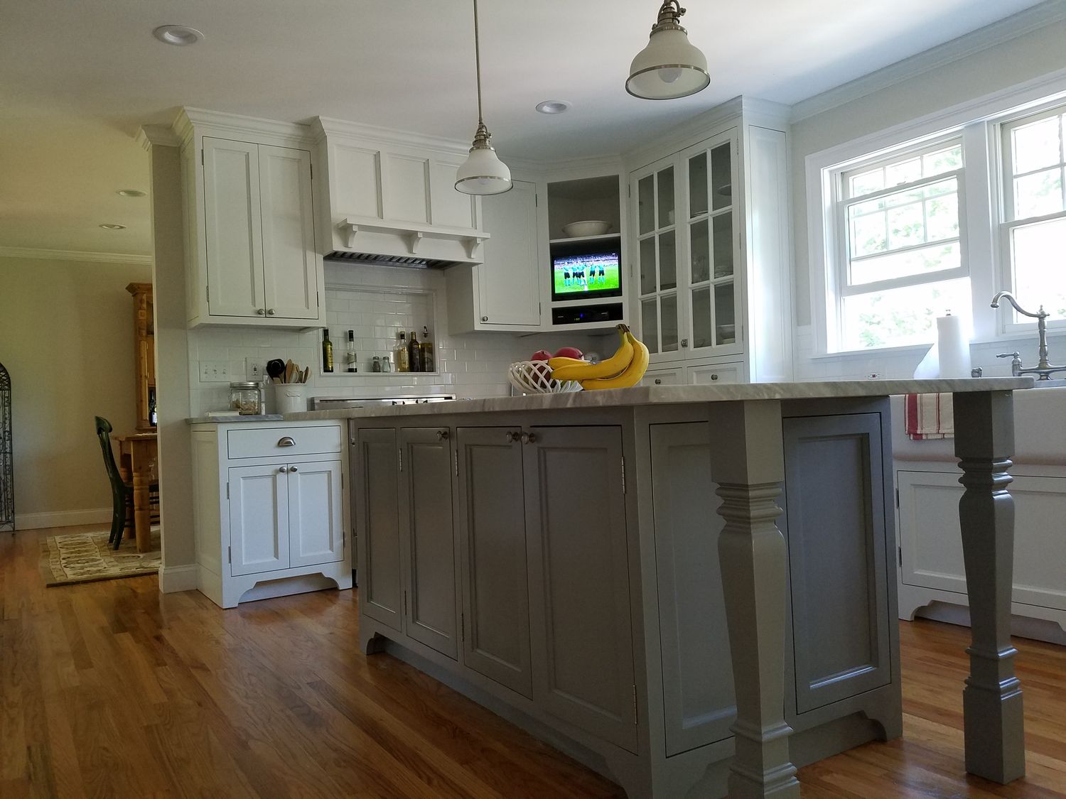 Cream inset custom kitchen with gray-green furniture-style island built by Division Seven Millwork