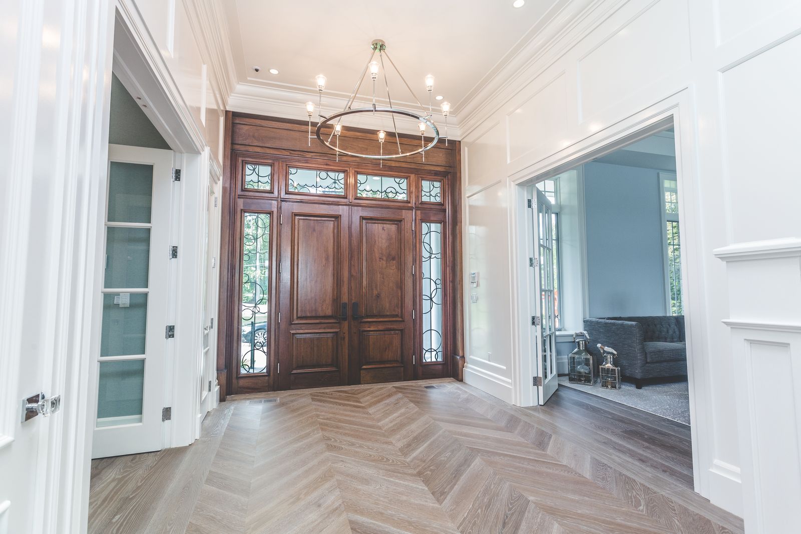 Entry foyer with wood double door, sidelites, and wainscoting millwork by Division Seven Millwork