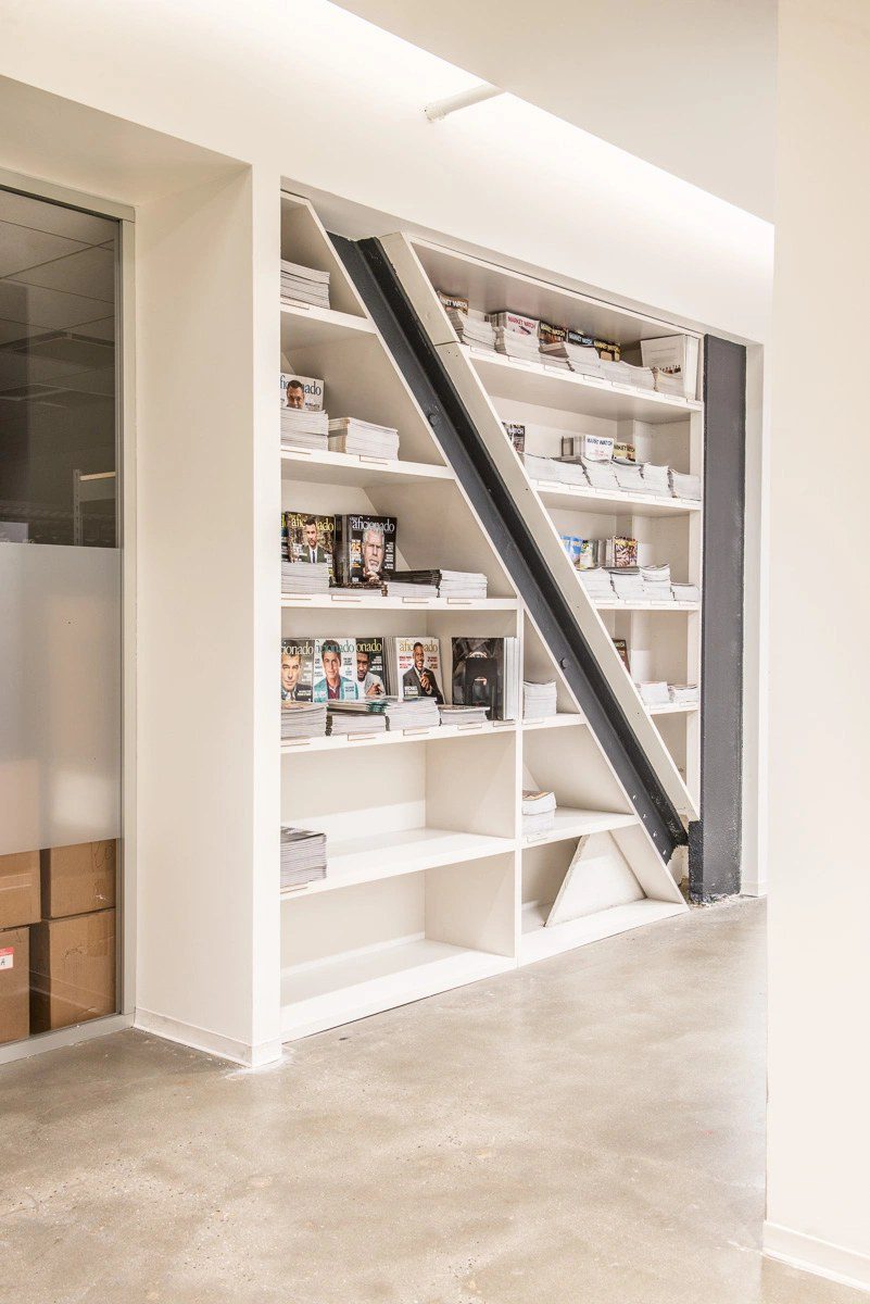 Custom white built-in shelving fitted around an exposed steel beam by Division Seven Millwork